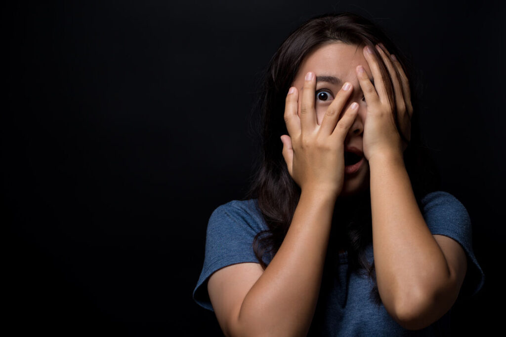 A woman covering her eyes with her hands, expressing surprise or shielding herself from light.